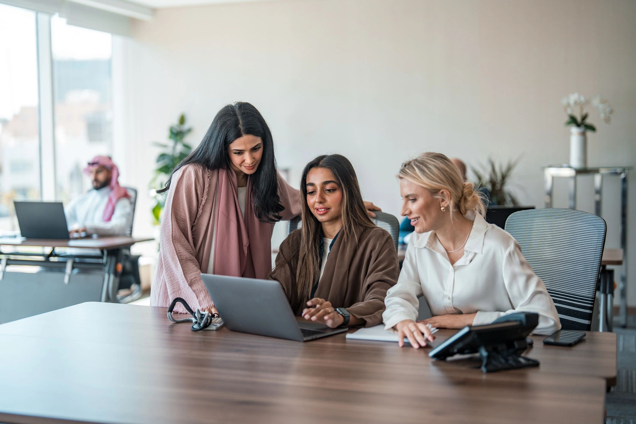 Business team collaborating around laptops in a modern office